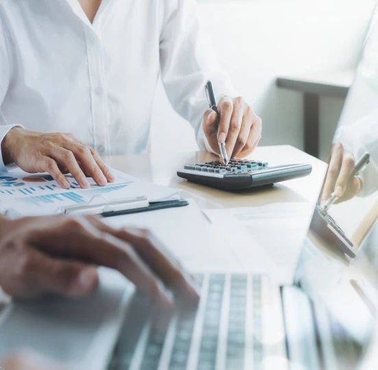 Profissionais de contabilidade trabalhando com calculadora, relatórios e computador