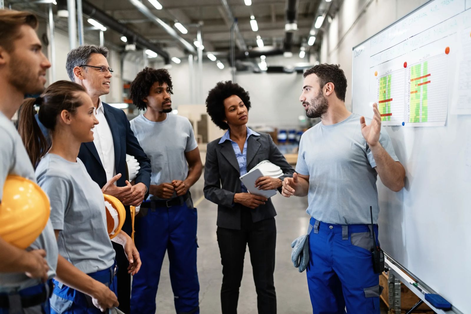 Equipe reunida diante de um quadro de planejamento em ambiente industrial